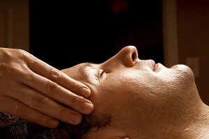 man getting a massage facial from therapist
